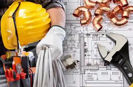 Assorted construction and engineering tools arranged on top of detailed blueprints. A gloved hand holds a bundle of electrical cables, with a yellow hard hat and tool belt containing pliers and screwdrivers nearby. Copper pipe fittings and an adjustable wrench rest on the plans, symbolizing the overlap of electrical, plumbing, and mechanical trades in construction work.